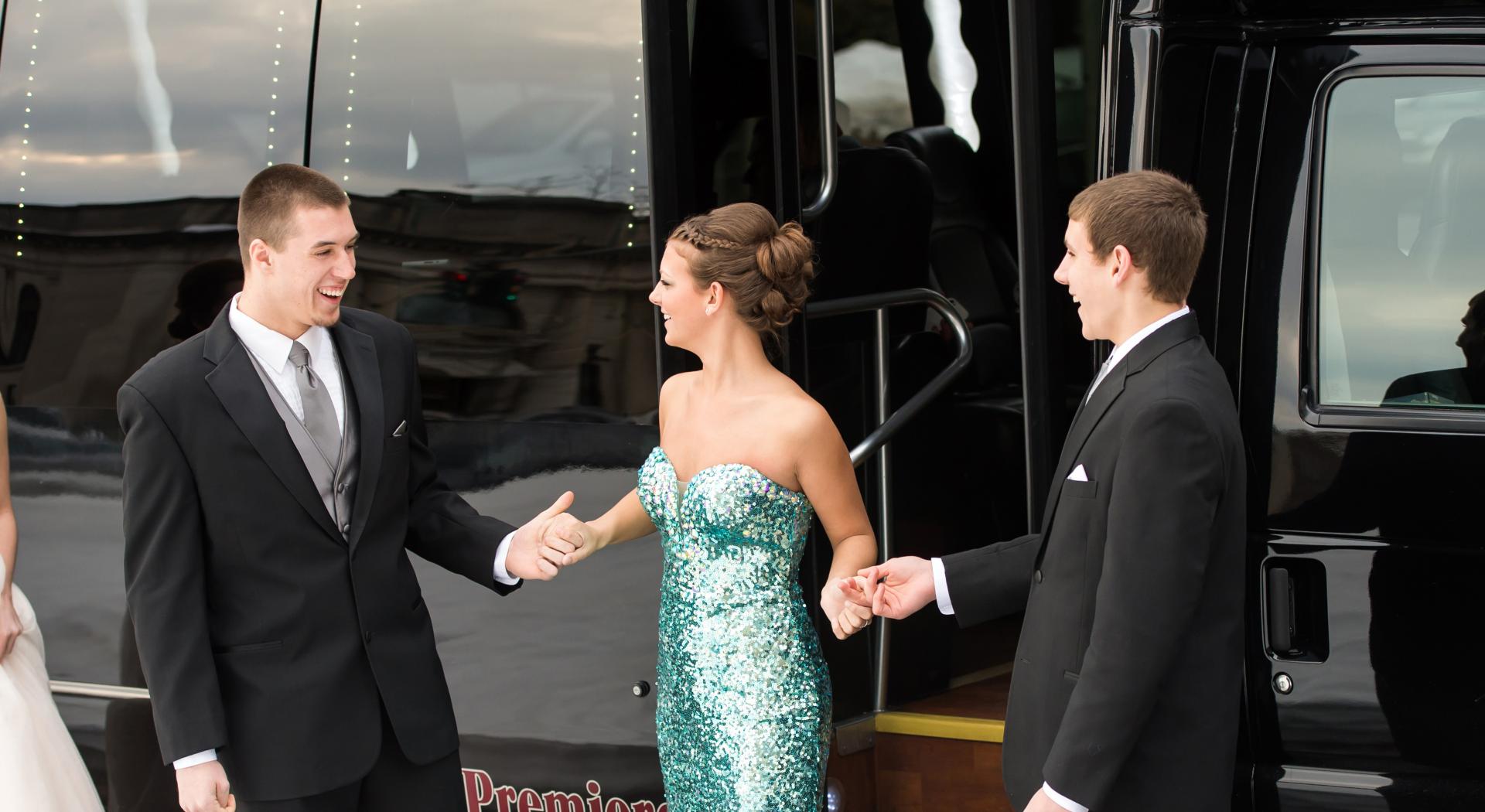 Teenagers dressed for prom in front of bus